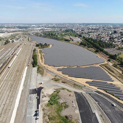 Panneaux solaires entre une ville et un réseau ferré