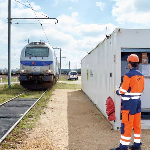 Agent SNCF Réseau devant un train de fret